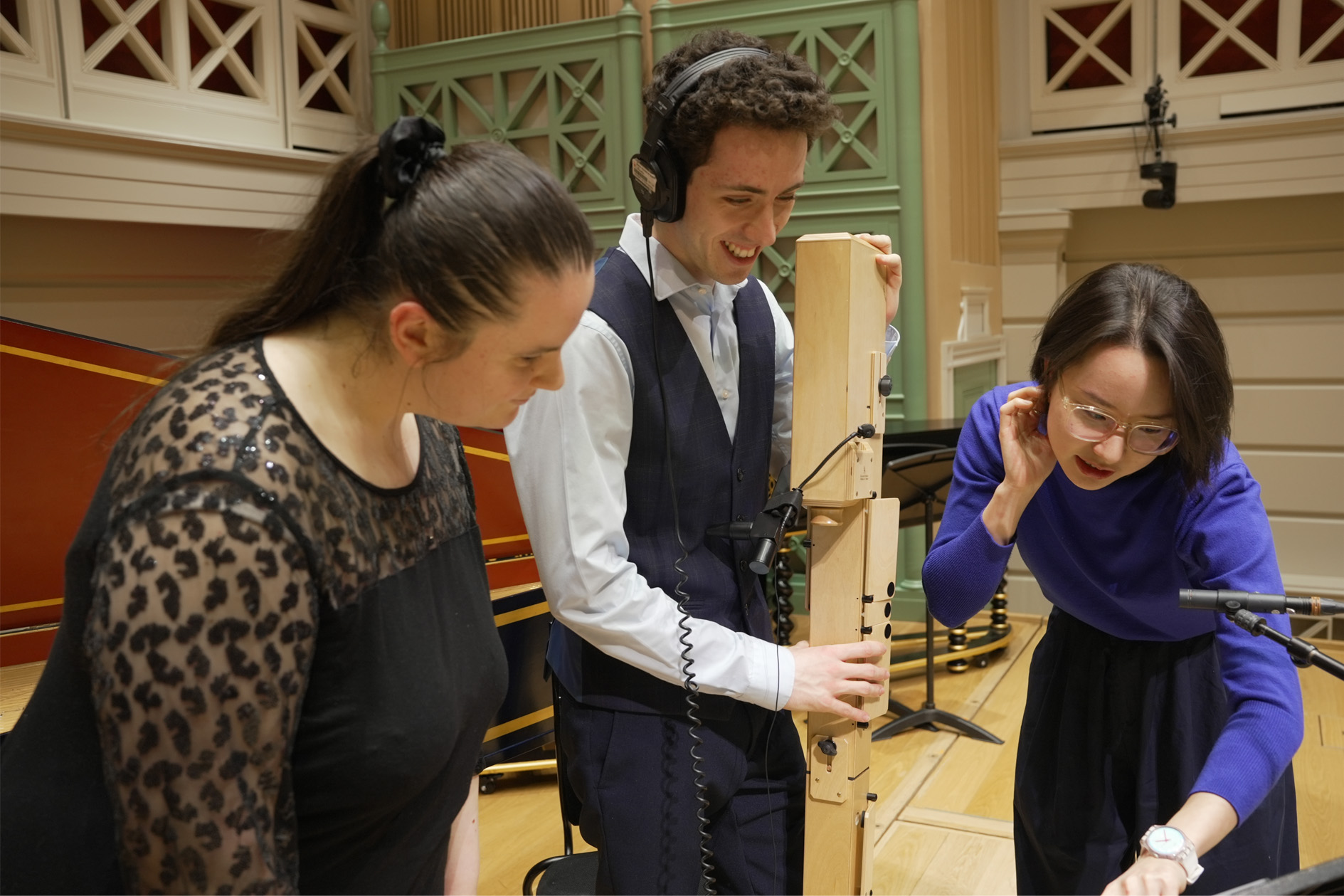 A group of students wearing smart clothes, looking at music sheets on stage.